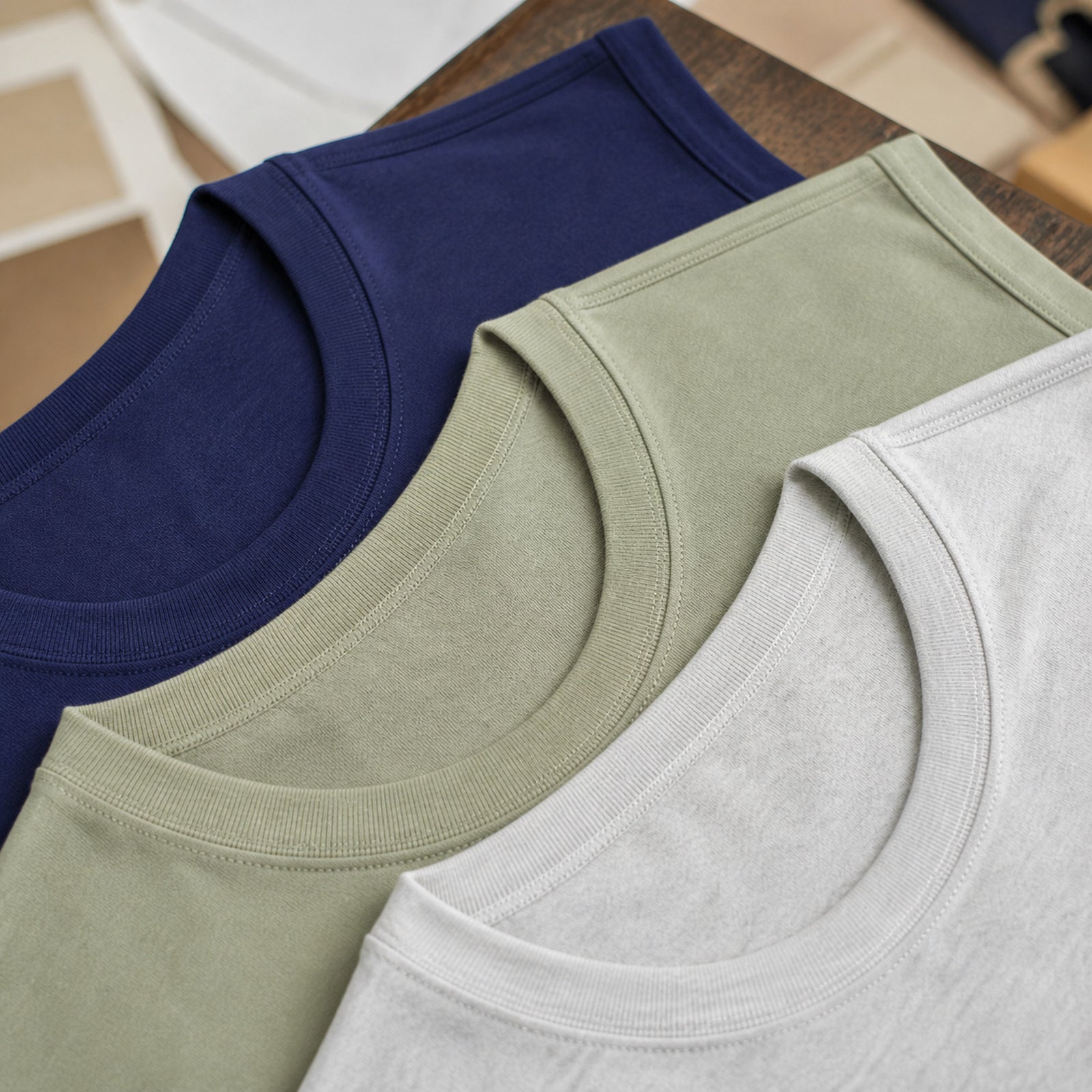Stacked navy, sage green and off-white heavyweight tanks, fabric close-up