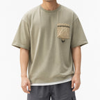 Man wearing the sage green utility tee with contrast crinkle pocket and grey shorts