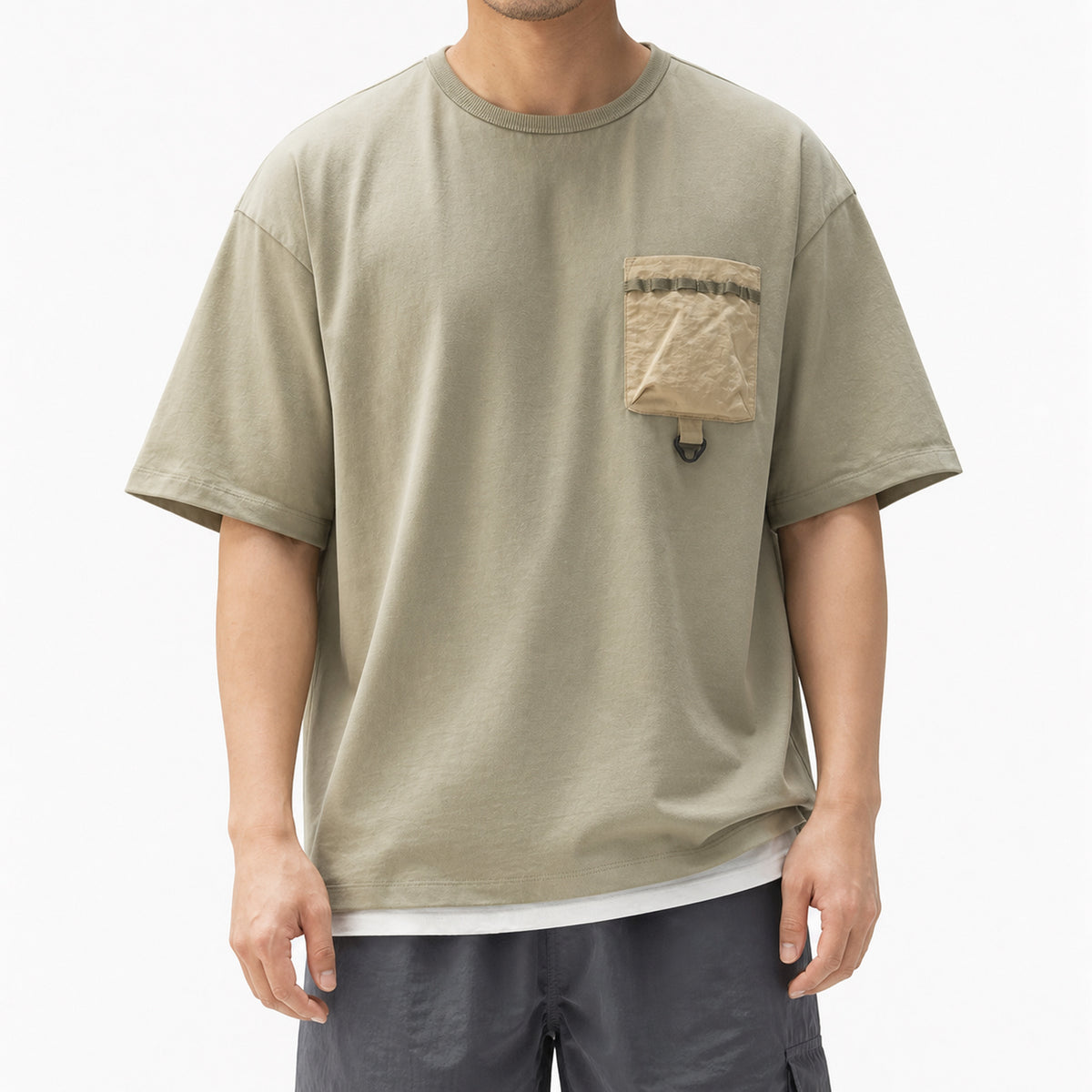 Man wearing the sage green utility tee with contrast crinkle pocket and grey shorts