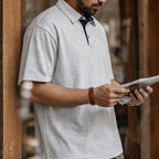 Man in the heather grey retro polo reading by a window