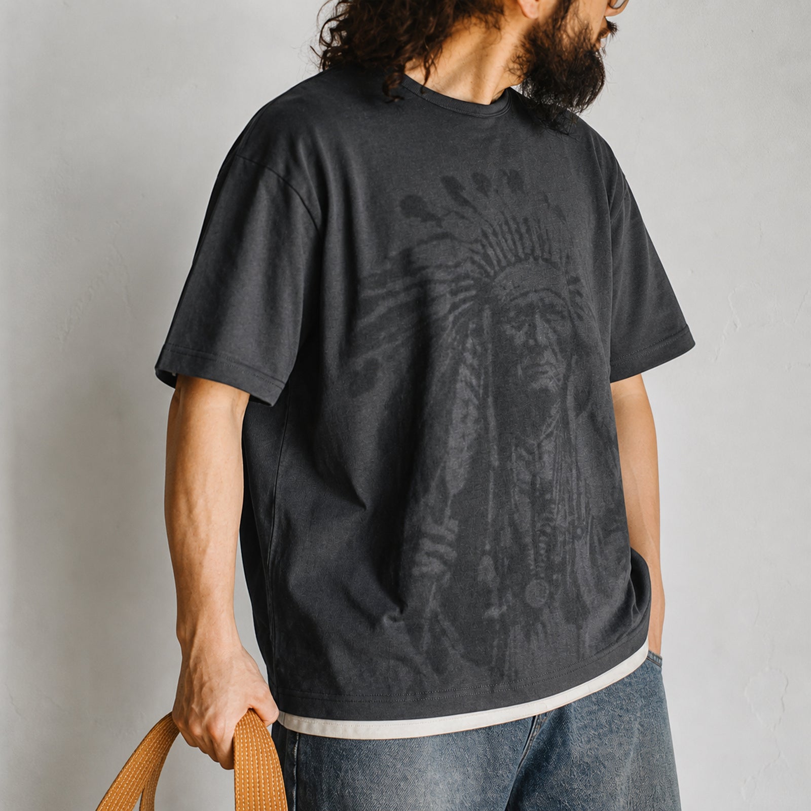 Man in the gray chief portrait tee with wide jeans, side view