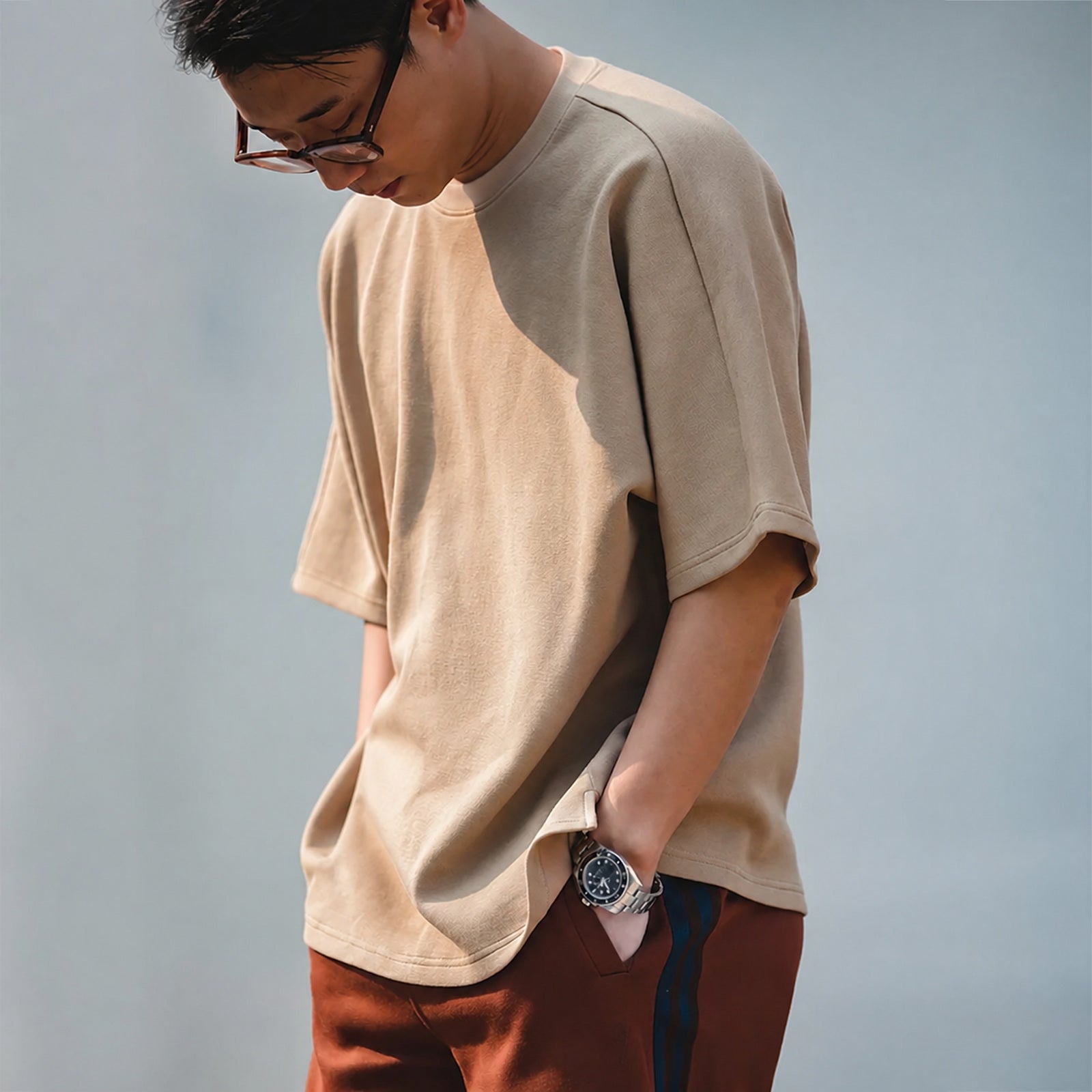 Man wearing the khaki oversized boxy tee with rust trousers