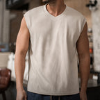 Man in the khaki ribbed v-neck tank with blue jeans, front view