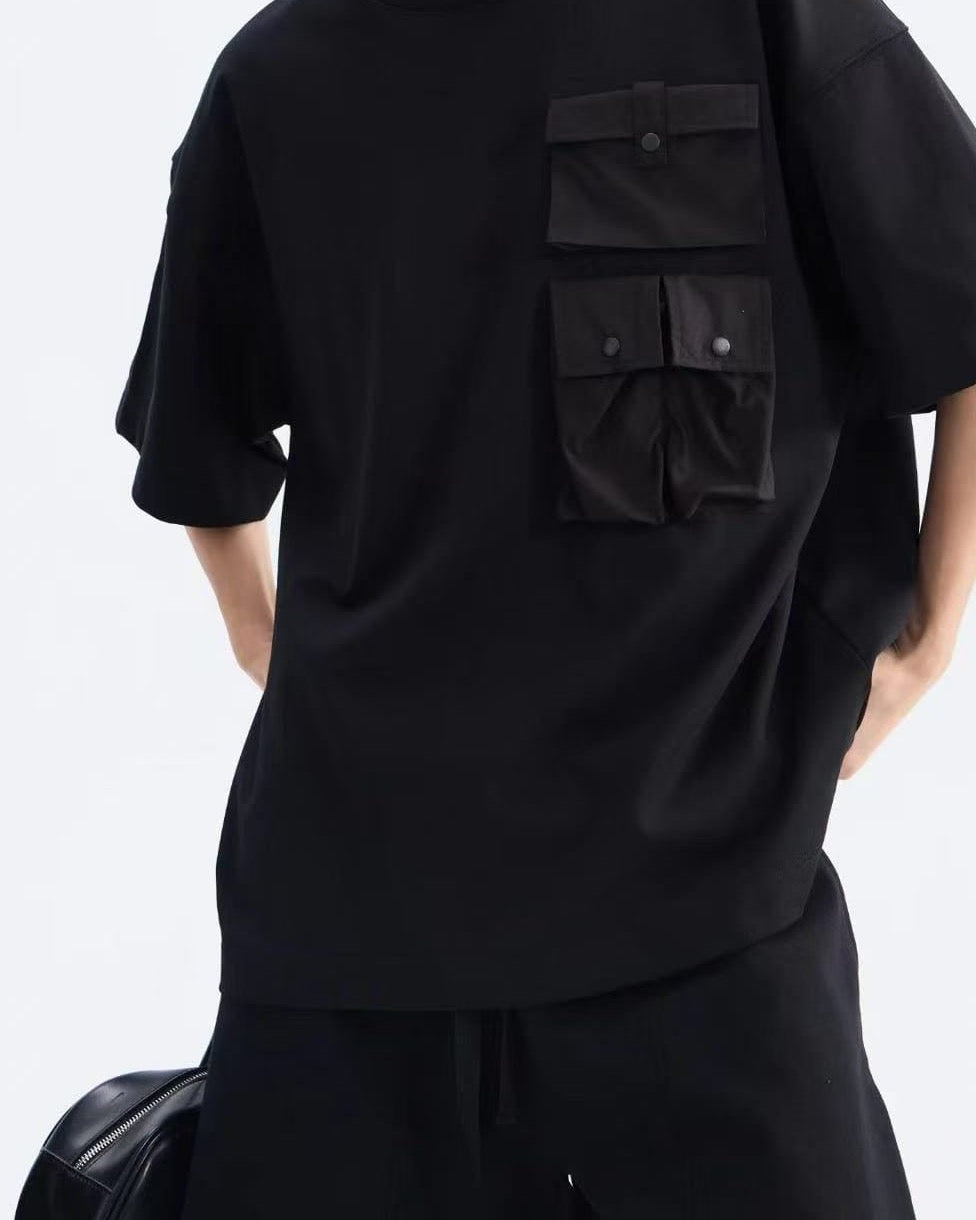 Front detail of the black oversized tee with dropped shoulder and snap-flap chest pocket, drawcord shorts waist below