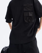 Front detail of the black oversized tee with dropped shoulder and snap-flap chest pocket, drawcord shorts waist below