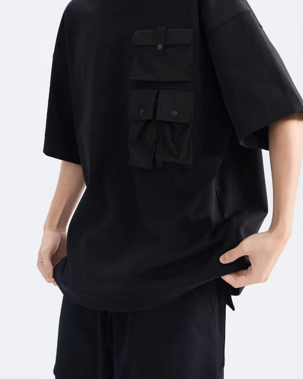Close-up of the stacked snap-flap chest pocket on the black oversized tee