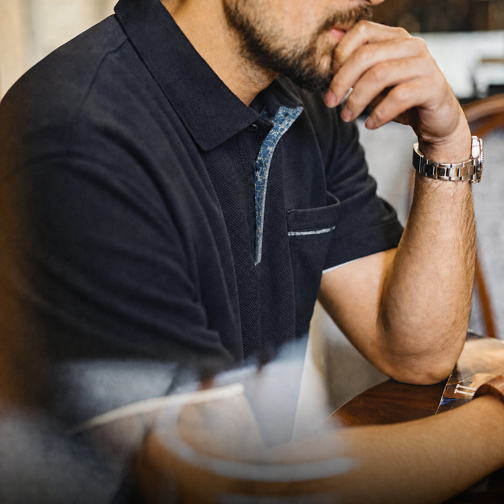Seated man in the navy polo showing the indigo placket trim