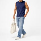 Man wearing the navy blue muscle tank with light jeans, full view